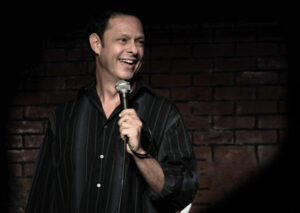 Comedian Flip Orley on stage holding a microphone