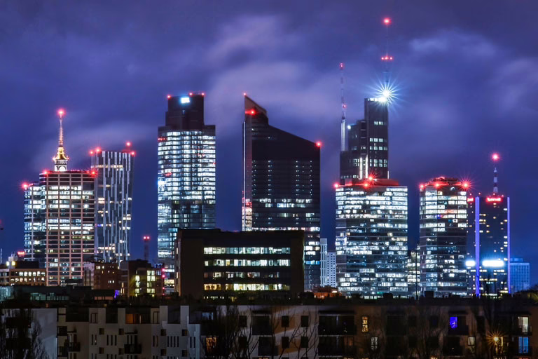Warsaw skyline at night with modern office towers, representing digital growth and infrastructure for small business hosting